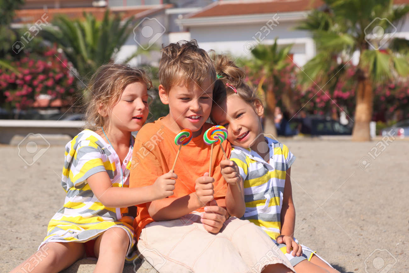 12627329-little-boy-and-two-girls-sitting-on-beach-and-holding-multicolored--Stock-Photo.jpg